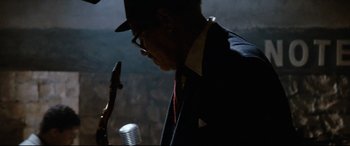 Movie still from “'Round Midnight” (1986), directed by Bertrand Tavernier – A man in a suit and hat looking at his cell phone; Close Up shot, Over the shoulder angle