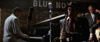 Movie still from “'Round Midnight” (1986), directed by Bertrand Tavernier – A man playing a saxophone in front of a microphone; Medium shot, Low angle