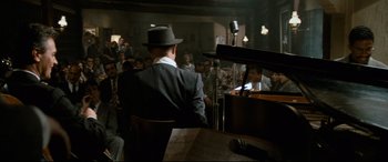 Movie still from “'Round Midnight” (1986), directed by Bertrand Tavernier – A man sitting at a piano in front of an audience; Wide shot, High angle
