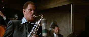 Movie still from “'Round Midnight” (1986), directed by Bertrand Tavernier – A man playing a saxophone in front of a microphone; Close Up shot, Low angle