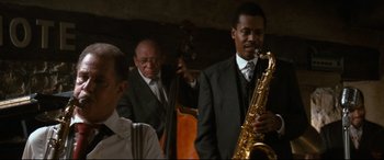 Movie still from “'Round Midnight” (1986), directed by Bertrand Tavernier – A group of men in suits and ties playing a musical instrument; Medium shot, Over the shoulder angle