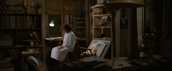 Movie still from “'Round Midnight” (1986), directed by Bertrand Tavernier – A woman sitting in a chair in a room; Wide shot, High angle