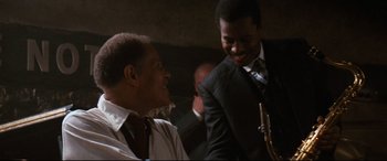 Movie still from “'Round Midnight” (1986), directed by Bertrand Tavernier – A couple of people that are playing a saxophone together; Close Up shot, Low angle
