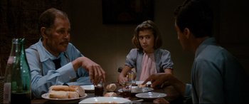 Movie still from “'Round Midnight” (1986), directed by Bertrand Tavernier – A group of people sitting at a table with plates of food on it; Medium shot, Over the shoulder angle