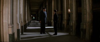 Movie still from “'Round Midnight” (1986), directed by Bertrand Tavernier – Two men in business suits are standing in a hallway; Wide shot, High angle