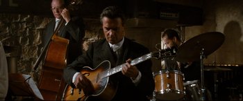 Movie still from “'Round Midnight” (1986), directed by Bertrand Tavernier – A man in a suit playing an instrument; Medium shot, Low angle