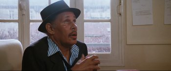 Movie still from “'Round Midnight” (1986), directed by Bertrand Tavernier – An older man wearing a black hat and a striped shirt; Close Up shot, High angle