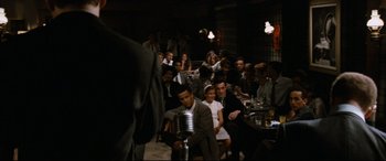 Movie still from “'Round Midnight” (1986), directed by Bertrand Tavernier – A group of people sitting at a table with microphones; Wide shot, High angle
