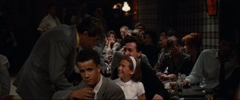 Movie still from “'Round Midnight” (1986), directed by Bertrand Tavernier – A group of people sitting in a room with wine glasses; Medium shot, Over the shoulder angle