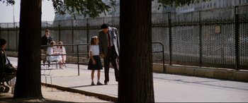 Movie still from “'Round Midnight” (1986), directed by Bertrand Tavernier – A man and a little girl standing next to a tree; Wide shot, Over the shoulder angle