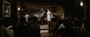 Movie still from “'Round Midnight” (1986), directed by Bertrand Tavernier – A man and a woman are performing in front of an audience; Wide shot, High angle