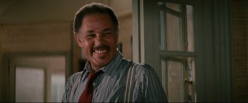 Movie still from “'Round Midnight” (1986), directed by Bertrand Tavernier – A man smiling for the camera while wearing a tie; Close Up shot, Low angle