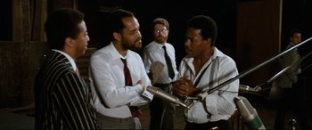 Movie still from “'Round Midnight” (1986), directed by Bertrand Tavernier – A group of men standing next to each other in front of microphones; Medium shot, Low angle