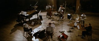 Movie still from “'Round Midnight” (1986), directed by Bertrand Tavernier – A group of people in a room with microphones and instruments; Extreme Wide shot, High angle