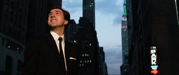 Movie still from “'Round Midnight” (1986), directed by Bertrand Tavernier – A man wearing a suit and tie standing in front of some buildings; Medium shot, Low angle