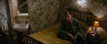 Movie still from “'Round Midnight” (1986), directed by Bertrand Tavernier – A man sitting on top of a wooden table; Wide shot, High angle