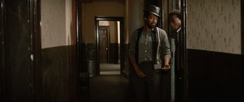 Movie still from “'Round Midnight” (1986), directed by Bertrand Tavernier – A man wearing a hat and a tie standing next to a woman; Medium shot, Over the shoulder angle