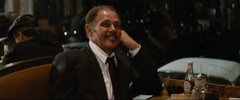 Movie still from “'Round Midnight” (1986), directed by Bertrand Tavernier – An older man wearing a suit and tie sitting at a table; Close Up shot, Over the shoulder angle