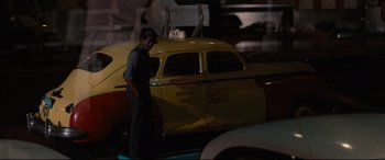 Movie still from “'Round Midnight” (1986), directed by Bertrand Tavernier – A man standing in front of a yellow taxi cab; Wide shot, Over the shoulder angle