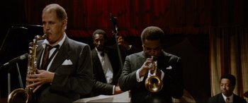 Movie still from “'Round Midnight” (1986), directed by Bertrand Tavernier – A man playing a trumpet in front of other men; Medium shot, Low angle