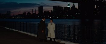 Movie still from “'Round Midnight” (1986), directed by Bertrand Tavernier – Two men standing next to each other near a body of water at night; Wide shot, Over the shoulder angle