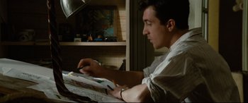 Movie still from “'Round Midnight” (1986), directed by Bertrand Tavernier – A man sitting at a table with a book in front of him; Medium shot, High angle