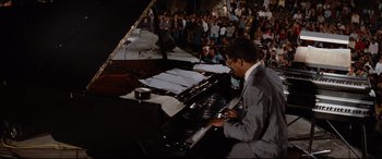 Movie still from “'Round Midnight” (1986), directed by Bertrand Tavernier – A man in a gray suit playing a piano; Wide shot, High angle