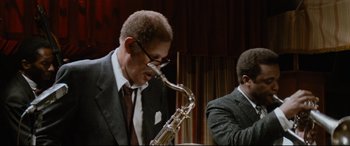 Movie still from “'Round Midnight” (1986), directed by Bertrand Tavernier – A man in a suit and tie playing a saxophone; Medium shot, Low angle