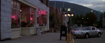 Movie still from “Roxanne” (1987), directed by Fred Schepisi – A neon cafe sign on the side of the street; Extreme Wide shot, High angle