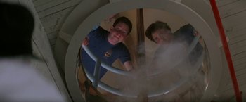 Movie still from “Roxanne” (1987), directed by Fred Schepisi – Two people are looking through a mirror in a room; Medium shot, Low angle