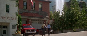 Movie still from “Roxanne” (1987), directed by Fred Schepisi – Two people walking down the street in front of a fire station; Extreme Wide shot, Low angle