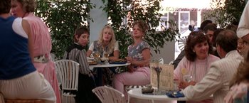 Movie still from “Roxanne” (1987), directed by Fred Schepisi – A group of people sitting at a table with wine glasses; Wide shot, Over the shoulder angle
