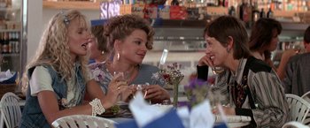 Movie still from “Roxanne” (1987), directed by Fred Schepisi – Two women are sitting at a table with wine glasses; Medium shot, Over the shoulder angle