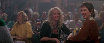 Movie still from “Roxanne” (1987), directed by Fred Schepisi – A group of people sitting in a room with drinks; Medium shot, Over the shoulder angle