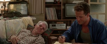Movie still from “Roxanne” (1987), directed by Fred Schepisi – Two people sitting at a table with a pen and paper in front of them; Medium shot, Over the shoulder angle