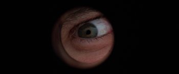 Movie still from “Roxanne” (1987), directed by Fred Schepisi – A person's eye looking through a magnifying glass; Extreme Close Up shot, Overhead angle