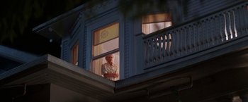 Movie still from “Roxanne” (1987), directed by Fred Schepisi – An older man standing in a window sill looking out of the window; Wide shot, Low angle