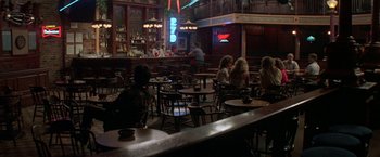 Movie still from “Roxanne” (1987), directed by Fred Schepisi – People are sitting at tables in a bar; Wide shot, High angle