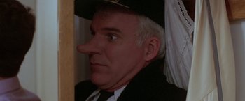 Movie still from “Roxanne” (1987), directed by Fred Schepisi – A person wearing a suit and a hat; Close Up shot, Over the shoulder angle