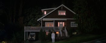 Movie still from “Roxanne” (1987), directed by Fred Schepisi – A person standing in front of a house at night; Extreme Wide shot, Low angle
