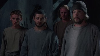 Movie still from “Royal Deceit” (1994), directed by Gabriel Axel – A group of men standing next to each other in a dark room; Medium shot, High angle