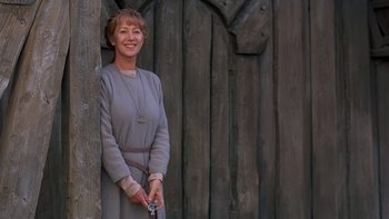 Movie still from “Royal Deceit” (1994), directed by Gabriel Axel – A woman standing next to a wooden fence; Medium shot, Low angle