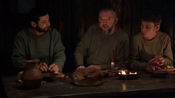 Movie still from “Royal Deceit” (1994), directed by Gabriel Axel – A group of people sitting at a table with food; Medium shot, Low angle