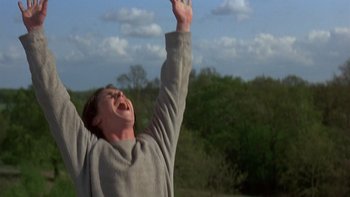 Movie still from “Royal Deceit” (1994), directed by Gabriel Axel – A man in a gray sweatshirt is raising his hands; Medium shot, Low angle