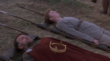Movie still from “Royal Deceit” (1994), directed by Gabriel Axel – Two men laying on the ground with a crown on their head; Medium shot, High angle