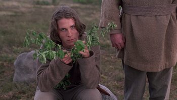 Movie still from “Royal Deceit” (1994), directed by Gabriel Axel – A man holding a bunch of green leaves; Medium shot, Low angle