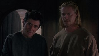 Movie still from “Royal Deceit” (1994), directed by Gabriel Axel – Two men standing next to each other in a dark room; Medium shot, Low angle