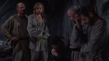 Movie still from “Royal Deceit” (1994), directed by Gabriel Axel – A group of people in a dark room; Medium shot, High angle