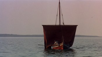 Movie still from “Royal Deceit” (1994), directed by Gabriel Axel – A small red boat floating on top of a body of water; Extreme Wide shot, Low angle