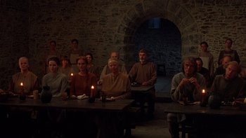 Movie still from “Royal Deceit” (1994), directed by Gabriel Axel – A group of people sitting at a table with candles; Wide shot, High angle
